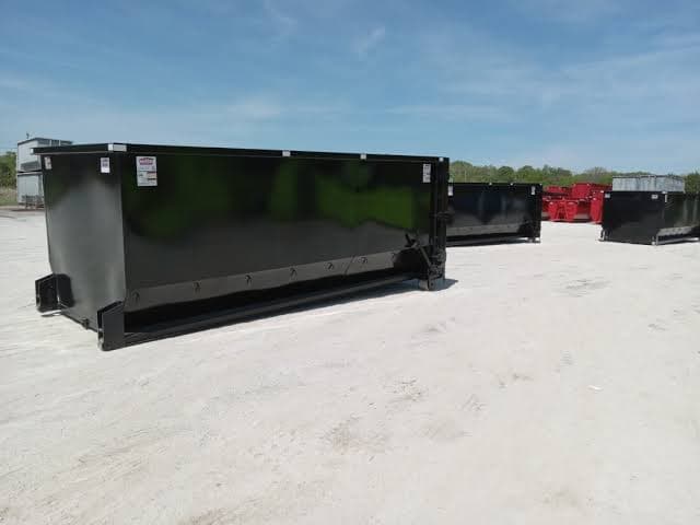 Multiple large roll-off dumpsters staged in a commercial lot