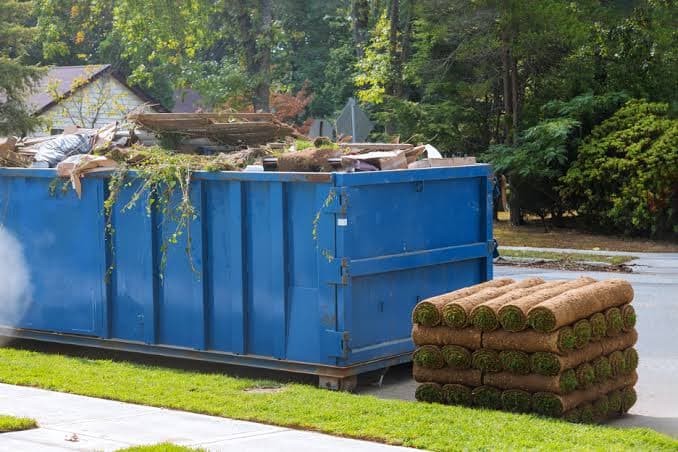 A dumpster filled with yard debris and household junk during an active cleanout
